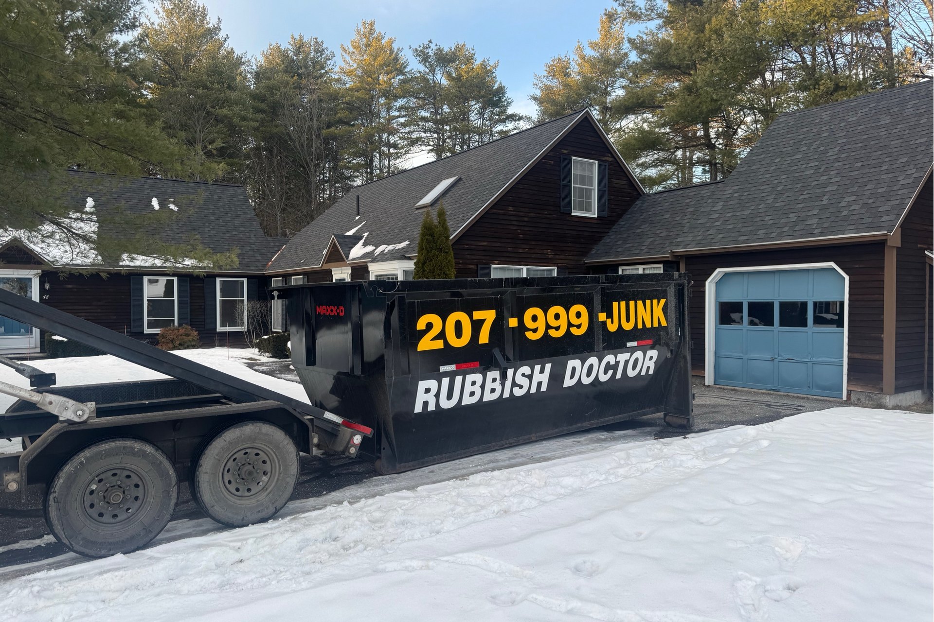 A Rubbish Doctor roll-off dumpster and service truck at a residential property cleanup